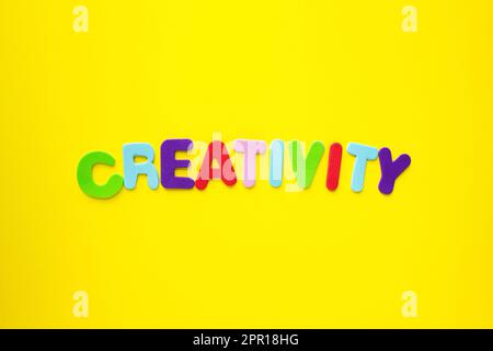 Parola creativa con lettere alfabetiche colorate isolate su sfondo giallo come intestazione banner con spazio copia. Foto Stock