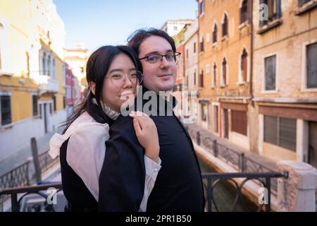 Una coppia mista di amanti abbraccia durante le vacanze a Venezia, la città dell'amore Foto Stock