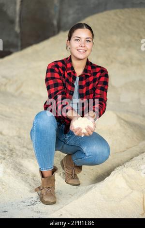 Donna agronomo positiva che squatting a mazzo di farina di mais Foto Stock