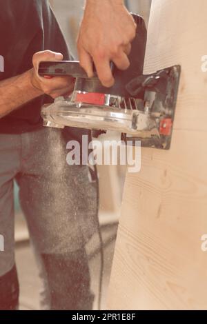 Uomo in azione al lavoro con strumenti potenti. Il falegname leviga una superficie di legno. Le vecchie fresatrici non vengono più utilizzate. Foto Stock
