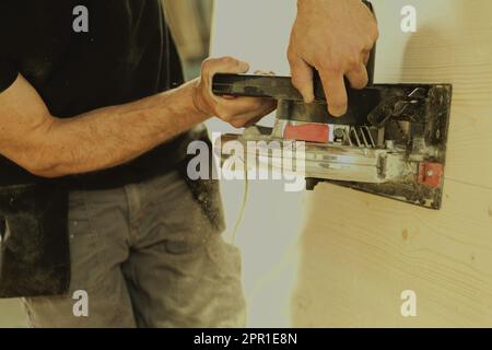 Uomo in azione al lavoro con strumenti potenti. Il falegname leviga una superficie di legno. Le vecchie fresatrici non vengono più utilizzate. Foto Stock