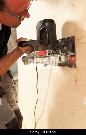 Uomo in azione al lavoro con strumenti potenti. Il falegname leviga una superficie di legno. Le vecchie fresatrici non vengono più utilizzate. Foto Stock
