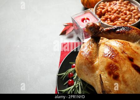 Festa tradizionale del giorno del Ringraziamento con deliziosi tacchino cotto e altri piatti di stagione serviti sul tavolo grigio, primo piano. Spazio per il testo Foto Stock