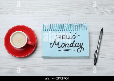 Messaggio Ciao Lunedi scritto in notebook, penna e tazza di caffè su scrivania di legno bianco, piatto Foto Stock