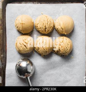 Misurini di pasta di biscotto di vaniglia su una sfoglia di biscotto rivestita di pergamena, pasta di biscotto di vaniglia semplice circa da cuocere Foto Stock