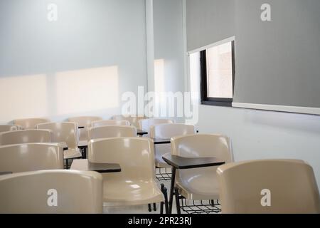 Classi vuote all'università o alla scuola con sedie e tavoli laterali, le sedie sono disposte in file. Foto Stock