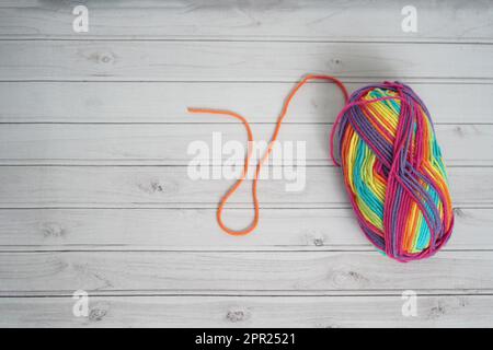 Arte e artigianato sfondo. Lana colorata per la lavorazione su uno sfondo di legno bianco. Spazio di sfondo di artigianato di lana per la scrittura. Foto Stock