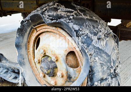 Una grande ruota di gomma nera arrugginita con una lacerazione usurata rotta vecchia piena di pneumatici pneumatico insicuro. Foto Stock