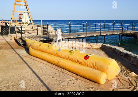 Gommone giallo in forma di banana per il divertimento dei turisti si trova sulla spiaggia vicino al molo nel mare tropicale resort in Egitto Foto Stock