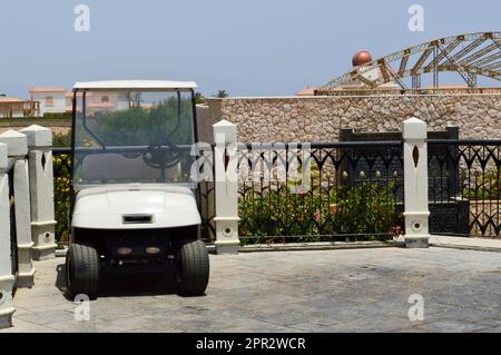 Le auto da golf elettriche bianche sono parcheggiate in piccoli veicoli elettrici con le tende dal sole in un paese caldo tropicale esotico resort di villeggiatura del sud. Foto Stock