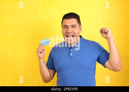 L'uomo adulto Latino dai capelli scuri di 40 anni mostra la sua carta di credito molto felice di essere in grado di fare acquisti e di avere finanze sane Foto Stock