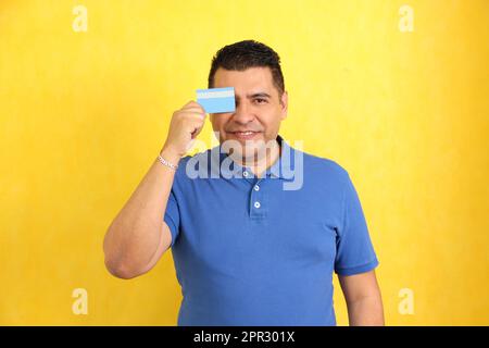 L'uomo adulto Latino dai capelli scuri di 40 anni mostra la sua carta di credito molto felice di essere in grado di fare acquisti e di avere finanze sane Foto Stock