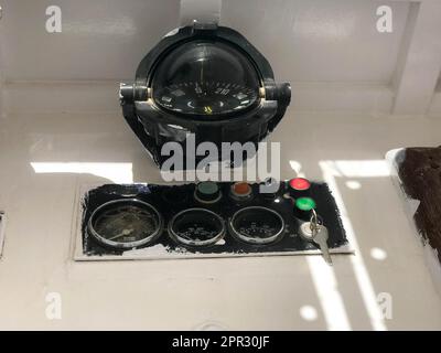 Cruscotto su barca, nave, trasporto marittimo con bussola rotonda, contagiri, tachimetro, chiave di accensione e pulsanti. Foto Stock