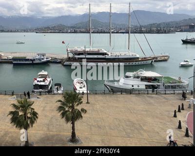 Molte navi, barche, navi da crociera nel porto e acqua sul mare tropicale caldo resort estivo con palme contro il cielo blu e alte montagne. Foto Stock