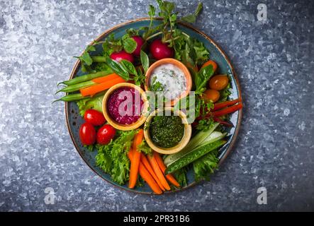 Piatto di verdure crudite con tre diversi salse su fondo metallico Foto Stock