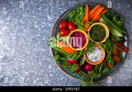 Piatto di verdure crudite con tre diversi salse su fondo metallico Foto Stock