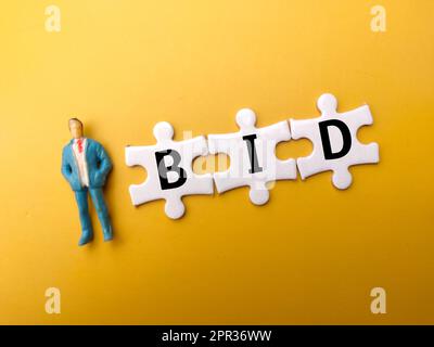 Persone in miniatura e puzzle bianco con la parola OFFERTA su sfondo giallo. Foto Stock