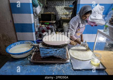 Donna che prepara i fogli di pasta per preparare dolci tipici marocchini in una bancarella di strada nella medina di Asilah. Foto Stock