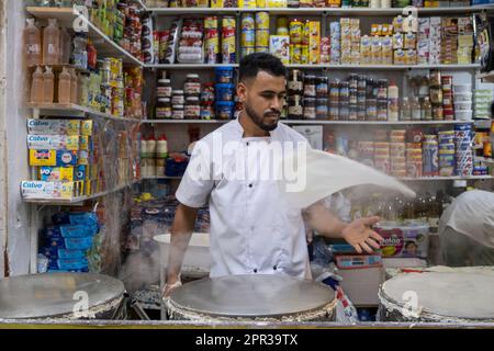 Uomo che prepara i fogli di pasta per preparare i dolci tipici marocchini in una bancarella di strada nella medina di Tangeri. Foto Stock