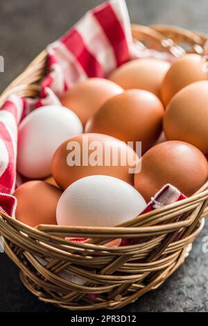 Uova intere di pollo nel cestino sul tavolo nero. Foto Stock