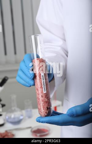 Scienziato che tiene in laboratorio, in primo piano, una provetta con carne macinata cruda coltivata Foto Stock