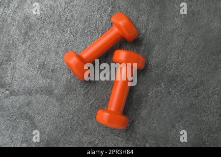 Due manubri arancioni su tavolo grigio, piatto Foto Stock