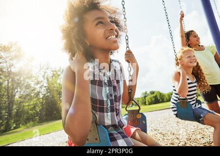 I bambini imparano a conoscere se stessi e il mondo attraverso il gioco. ragazze giovani che giocano sulle altalene al parco. Foto Stock