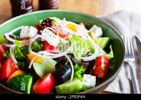 Insalata greca fresca con pomodoro, cetriolo, peperone, cipolla e formaggio feta su piatto verde, vista dall'alto. Insalata greca con verdure fresche e formaggio feta Foto Stock