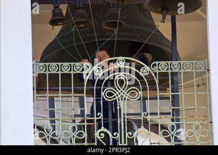 Luga. Russia. - 05.17.2020: Il giovane campanello sul campanile della cattedrale suona le grandi campane alla liturgia, al peal e al jingle Foto Stock