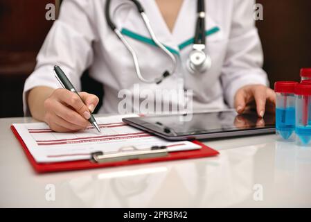 Il medico scrive un'analisi a raggi X nella storia medica dei pazienti. Primo piano Foto Stock