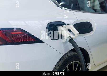 connettore del cavo della stazione di ricarica nella porta di ingresso di un moderno primo piano di un'auto elettrica per passeggeri Foto Stock