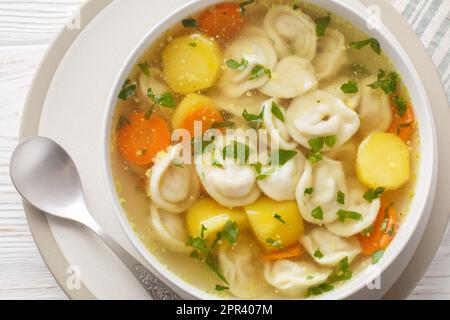 Deliziosa zuppa di gnocchi con carote, cipolle, patate e brodo di pollo in un piatto su un tavolo di legno. Vista orizzontale dall'alto Foto Stock