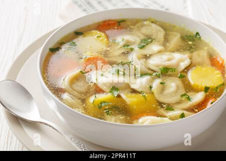Deliziosa zuppa di gnocchi con carote, cipolle, patate e brodo di pollo in un piatto su un tavolo di legno. Orizzontale Foto Stock