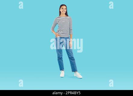 Foto integrale di una giovane donna in abiti casual in piedi su uno sfondo blu studio Foto Stock