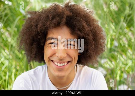 Ritratto di un bel giovane giovane giovane di razza mista sorridente all'aperto. Gli uomini multirazziali guardano la macchina fotografica con le emozioni positive di spazio verde, sensibilità.primo piano Foto Stock