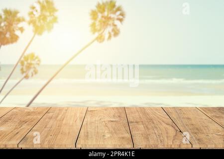 estate mare spiaggia palma con tavolo in legno primo piano spazio per la pubblicità prodotti montaggio sfondo vintage tonalità di colore Foto Stock