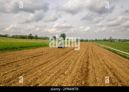 Castell'Arquato, Italia - Aprile 2023 contadino che guida trattori cingolati in aratura su campo asciutto prima di seminare il punto di vista aereo Foto Stock