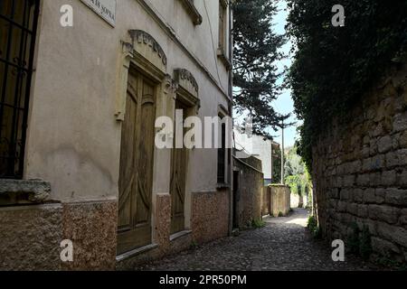 Strada stretta delimitata da un edificio e un muro di pietra in un parco sulla collina in primavera Foto Stock