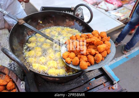 Preparazione di Pakoda Road Food Indian. Produzione croccante di Pakora di olio. Foto Stock