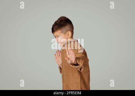 Disappaiato bambino piccolo triste 6 anni in abiti casual fa il gesto di arresto con le mani Foto Stock