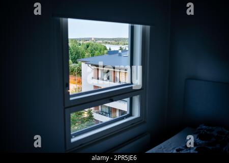Finestra in appartamento. Condominio casa di costruzione fuori, vicino. Camera buia. Affitto di alloggi o proprietà immobiliare. Strada in zona residenziale. Foto Stock
