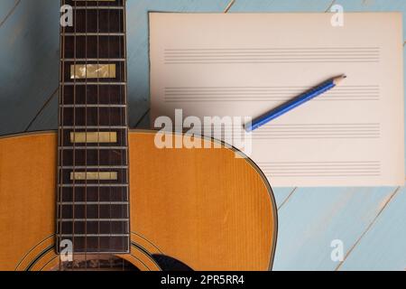 Scena di registrazione musicale con chitarra, foglio di musica vuoto e matita su tavolo di legno Foto Stock