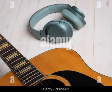 Scena di registrazione musicale con chitarra, spartiti vuoti, matita e cuffie su tavolo bianco in legno Foto Stock