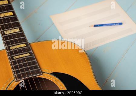 Scena di registrazione musicale con chitarra, foglio di musica vuoto e matita su tavolo di legno Foto Stock