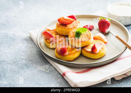 Frittelle di formaggio cottage, frittelle di ricotta o scironiki con menta e fragole. Sana e deliziosa colazione mattutina. Foto Stock