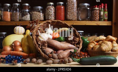 Cesti di verdure fresche e pane in cucina rustica con vasetti di cibo secco sullo sfondo Foto Stock