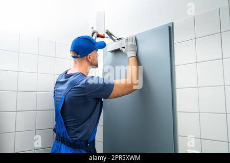 Tuttofare installazione e fissaggio del chiudiporta automatico Foto Stock