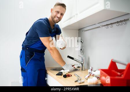 Plumber che fissa il rubinetto in cucina Foto Stock