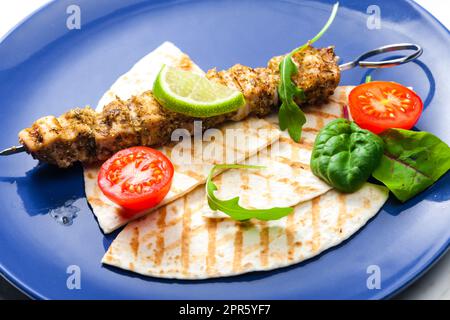 spiedino di carne alle erbe con pita pane, pomodori e lime Foto Stock