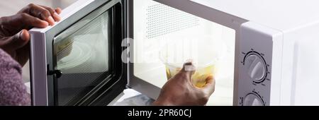 Man's Hand Heating Food in forno a microonde Foto Stock